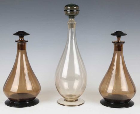 A pair of glass decanters and stoppers, probably Scandinavian, the pear shaped amber glass bodies with subtle vertical ribbed