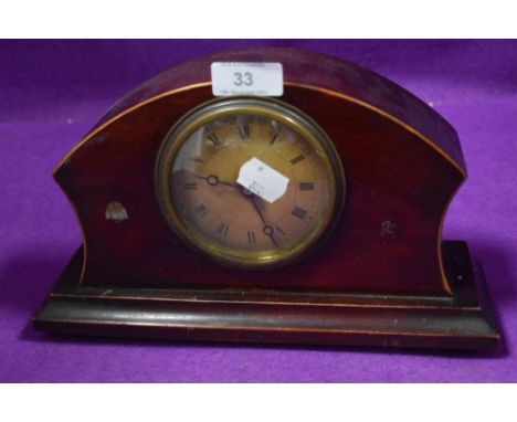 An early 20th century mantel clock having mahogany body and roman numerals to face.