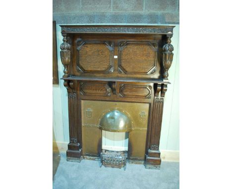 An early 20th century carved oak Fire Surround with foliate frieze, cup and cover balusters, mantle shelf and hooded copper i
