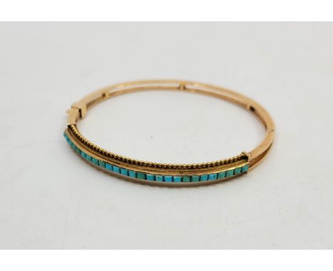 A French 18ct. gold and turquoise hinged bangle, of ovoid section, the front&nbsp;channel set numerous pyramidal cabochon tur