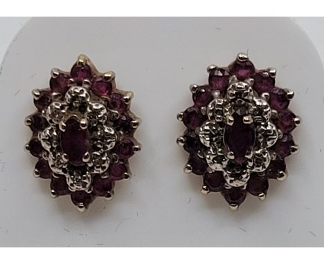 A pair of 9ct. gold, ruby and diamond cluster earrings, of navette form, the raised centre set single marquise cut ruby borde