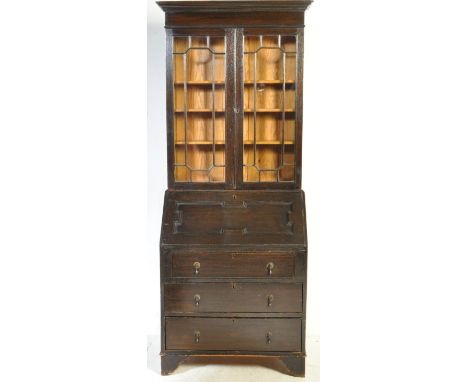 A Jacobean Revival circa 1920s oak bureau bookcase having a flared stepped top over a double door glazed cabinet opening to r