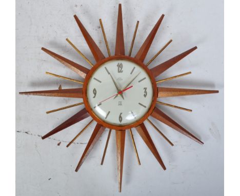 A mid century Smiths Time Cal teak wood sunburst wall clock. White dial with makers marks to centre having dagger hands and p