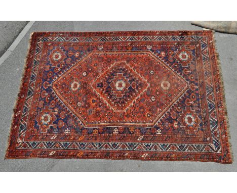 A 20th century Qashqai rug carpet having a central blue medallion set within a larger red medallion. The central border havin