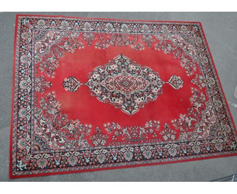 A vintage 20th century Persian Islamic carpet floor rug having a red background with a central floral medallion surrounded by