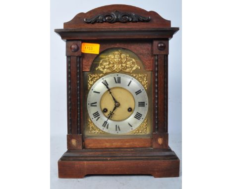 An early 20th century oak cased mantel clock having roman numeral to a silvered chapter ring with gilt spandrels to the surro