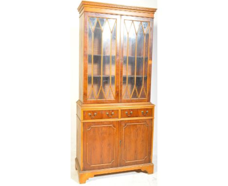 A 20th century Regency Revival yew wood library bookcase having a twin door cabinet with astragal glazing opening to reveal a
