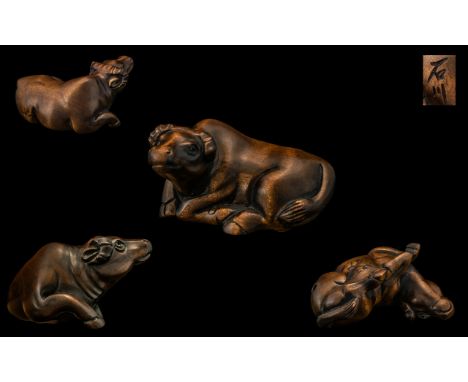 An Oriental Boxwood Netsuke in the form of water buffalo, signed to the base.  Please see accompanying images.