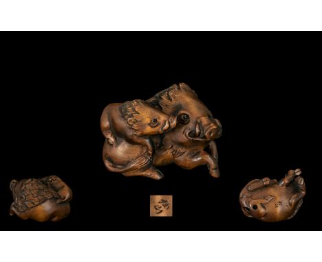 An Oriental Boxwood Netsuke in the form of two wild boars, signed to base. Please see accompanying images.