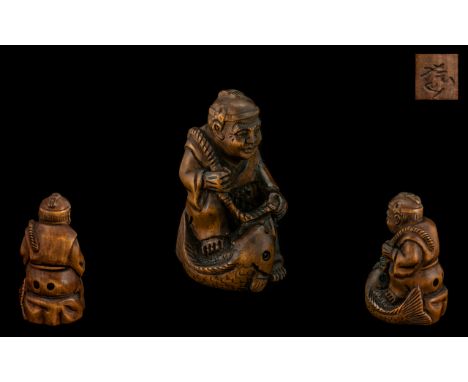 An Oriental Boxwood Netsuke in the form of a fisherman and his catch, signed to base.  Please see accompanying images.