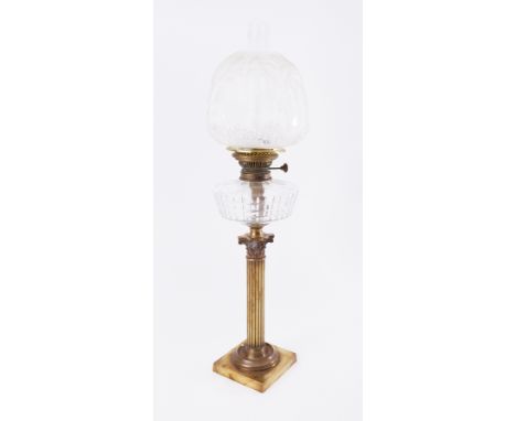 A Victorian oil lamp on brass column with glass reservoir and embossed shade.