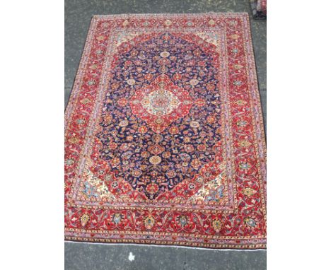 PERSIAN HAND KNOTTED WOOL CARPET, with a central lozenge with floral designs, in a surround of floral designs on blue, border