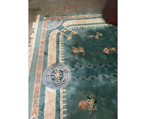 FINE FRINGED CHINESE CARPET, the central roundel with a dragon motif surrounded by a vase and flower ornaments on a green gro