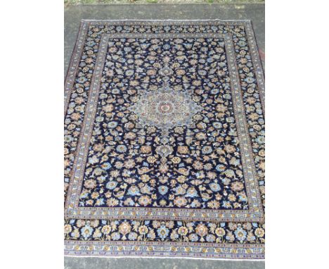 PERSIAN HAND KNOTTED WOOL CARPET, with a central roundel of floral designs, surrounded by floral designs on a blue ground and