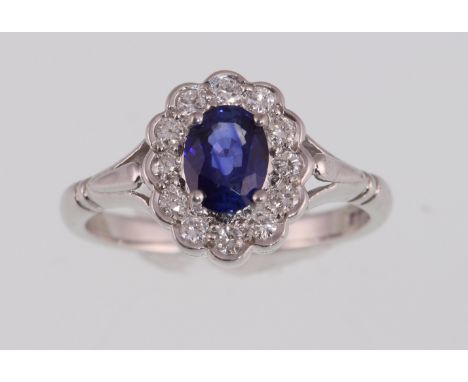 An 18ct white gold H/M sapphire & diamond floral cluster ring, the central oval sapphire surrounded by round brilliant cut di