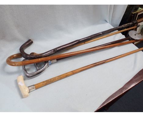 AN EDWARDIAN WALKING STICK with silver ferrule, others similar and a shooting stick