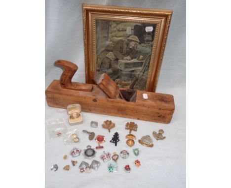 A COLLECTION OF MILITARY CAP BADGES, A WWI CARPENTER'S PLANE with broad arrow stamp, and a print of a Tommy writing home