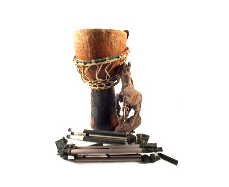 A carved wooden horse, clay drum and two camera tripods