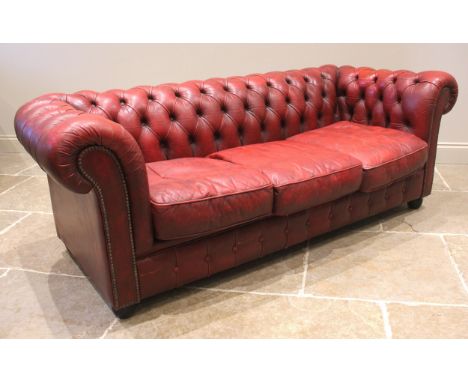 A red leather Chesterfield sofa, late 20th century, of deep set button back form, enclosing three loose cushions, 183cm wide,