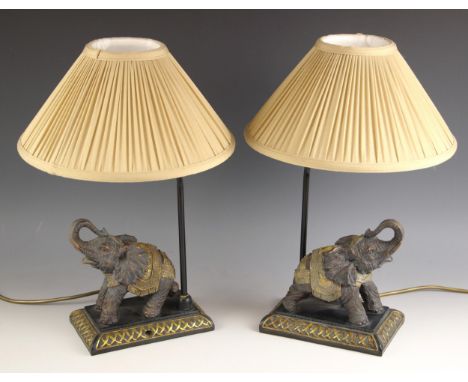A pair of novelty table lamps, each modelled as a caparisoned elephant with its trunk raised, with shade, each 37.5cm high in