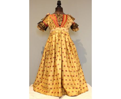 An 1840's Child's yellow figured silk dress, with an all-over floral pattern, with later alterations, on dummy Note; Illustra