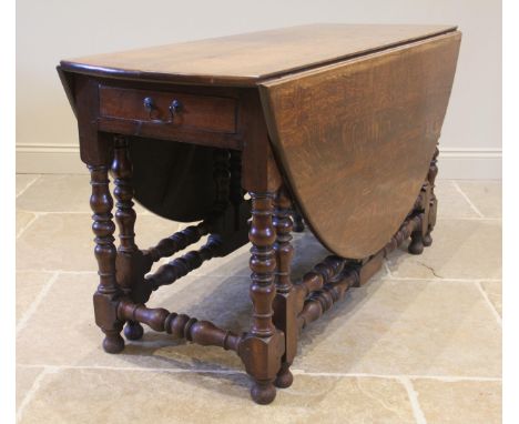 An 18th century oak drop leaf dining table, the oval top and single frieze drawer, upon bobbin turned supports and onion shap