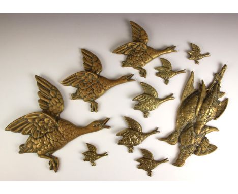 A set of three brass graduated birds, each modelled flying, 26cm high to 17cm high, and a brass model of hanging game birds, 