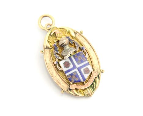 A yellow metal pedant, the oval pendant with applied enamel shield motif surmounted by a knight, with plain polished pendant 