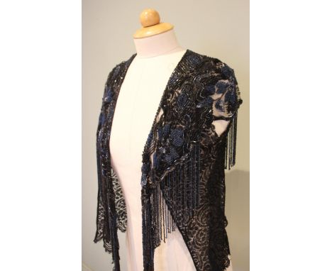 A black silk lace sleeveless jacket, circa 1930, overlaid with tulle shoulder cape embroidered with jet coloured and steel bl