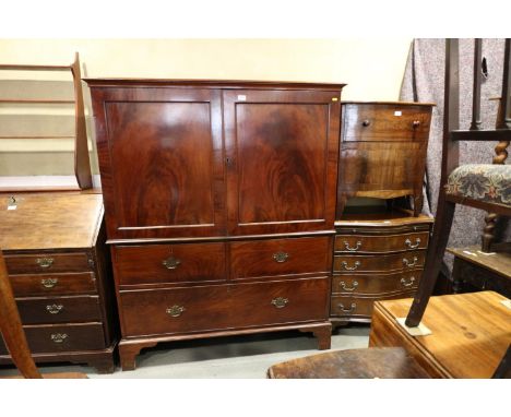 An early 19th century mahogany linen press, the upper section fitted trays enclosed two doors, over two short and one long dr
