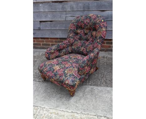 A late Victorian button back deep seat armchair, upholstered in a floral fabric, on turned and castored supports 