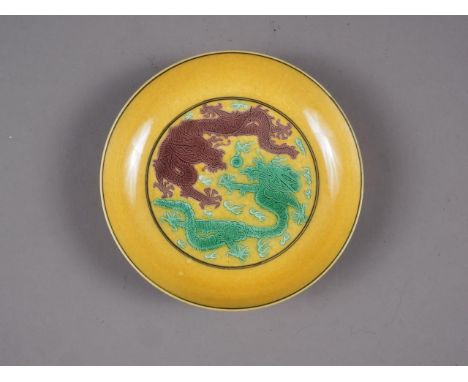A Chinese yellow glazed dish with two dragons and reverse decorated with grapes, seal mark to base, 5" dia 