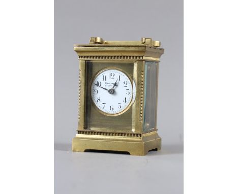 A brass cased carriage clock, white enamel dial inscribed "Harrods Ltd London SW", 6" high with raised handle 