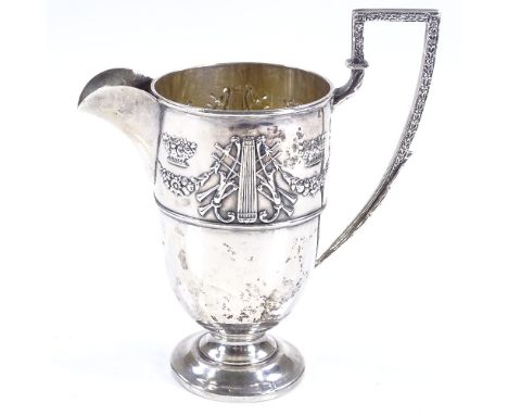 An Edwardian silver helmet-shaped cream jug, with relief embossed Adams style decoration, and gilt interior, by William Hutto