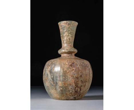 Ca. AD 300 - 400. A translucent pale green glass flask with an apple-shaped body and a concave base. The neck features a hori