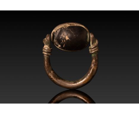 New Kingdom, Ca. 1550 - 1069 BC. A swivel ring with a black stone scarab, set within an oval bezel. The thick, rounded hoop i