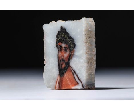 Ca. 30 BC - AD 200 or later. A glass inlay fragment with a polychrome depiction of Dionysus, shown with a beard, laurel wreat