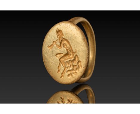 Ca. 450 BC.A gold ring with a flat circular bezel engraved with a satyr seated in profile on a pile of rocks, playing a flute