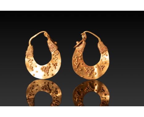 Ca. 300 - 100 BC. A matched pair of gold earrings, each composed of a flat, crescent-shaped sheet with tapering ends. The upp