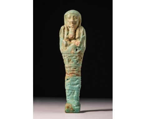 Late Period, 26th Dynasty, Ca. 550 BC. A blue glazed faience ushabti with arms crossed over the chest, holding a pick and hoe