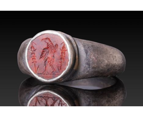 Ca. AD 100 - 200.A carnelian intaglio engraved with a legionary eagle standing on a groundline, flanked by two military stand