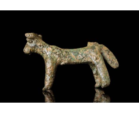 Ca. 700 BC. A cast bronze bull depicted in a standing pose, with short cylindrical legs and a compact body. The head is broad