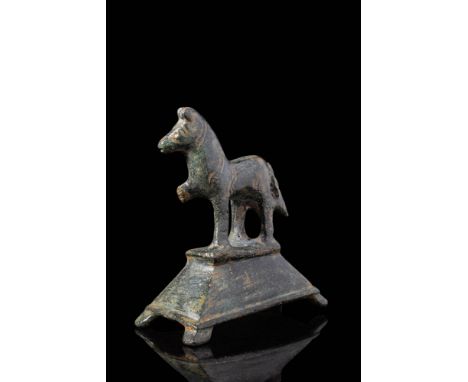 Ca. AD 1 - 200. A bronze figure of a horse standing atop an integral rectangular plinth. The body is rendered in a simplified