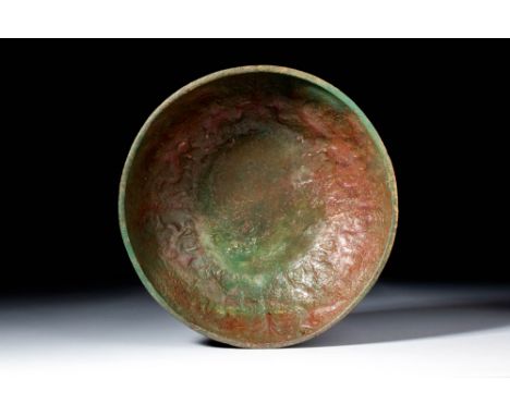 Ca. AD 1 - 300.A shallow bronze bowl with a wide hemispherical body depicting a procession of camels. The rim is plain and su