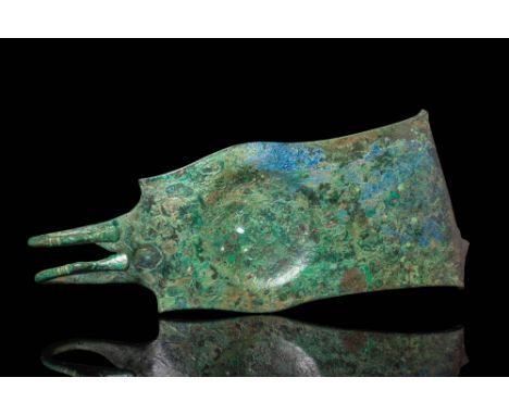 Ca. 800 - 700 BC.A bronze belt fitting with an elongated, flaring form with raised edges and a large boss. The surface is dec