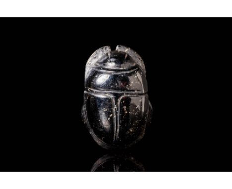 Late Period, Ca. 664 - 332 BC. A black scarab with a convex, dorsal surface, delineated by deeply incised lines marking the h