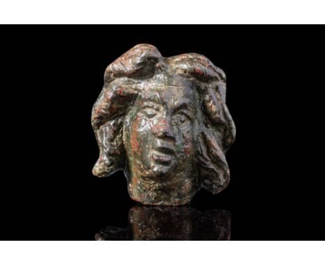Ca. AD 1 - 200. A cast bronze head of Medusa. Her face is modelled with a prominent brow, wide nose, and parted lips. Eyes ar