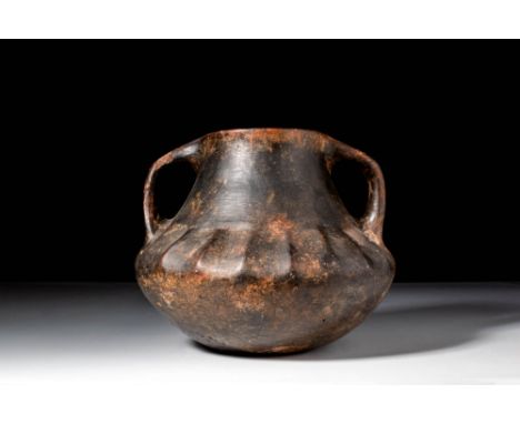 Ca. 750 - 600 BC. A pottery kantharos with a sharply carinated lower body and twin arched handles extending from the rim to t