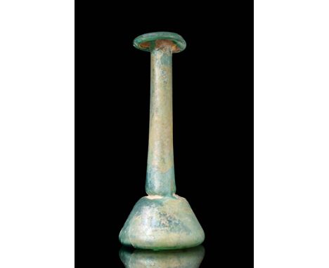 Ca. AD 1 - 200. A pale blue glass candlestick unguentarium with a bell-shaped body that narrows into a long cylindrical neck,