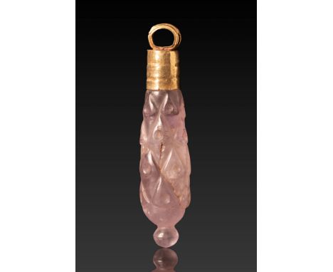 Ca. 300 BC. A pendant with a carved amethyst drop, set in a cylindrical gold cap with a suspension loop. The amethyst is shap
